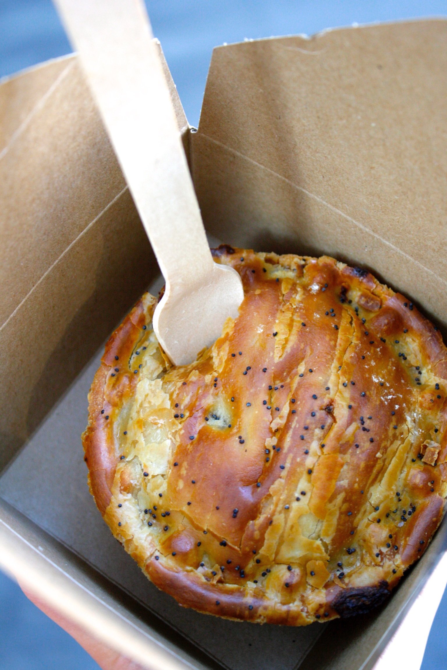Savory golden Pieminister pie in a takeout container with a fork sticking out