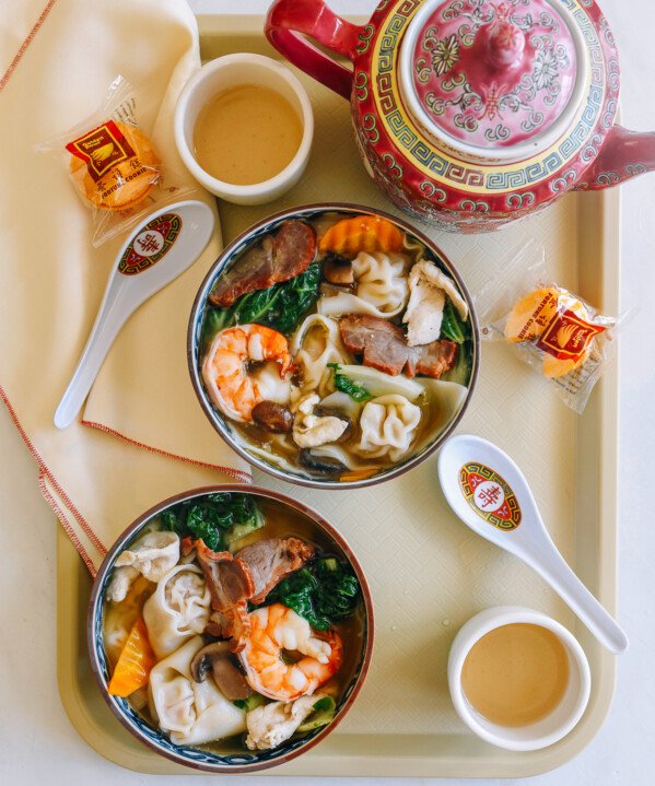 Bowls of Wor Wonton Soup on a tray with fortune cookies and tea