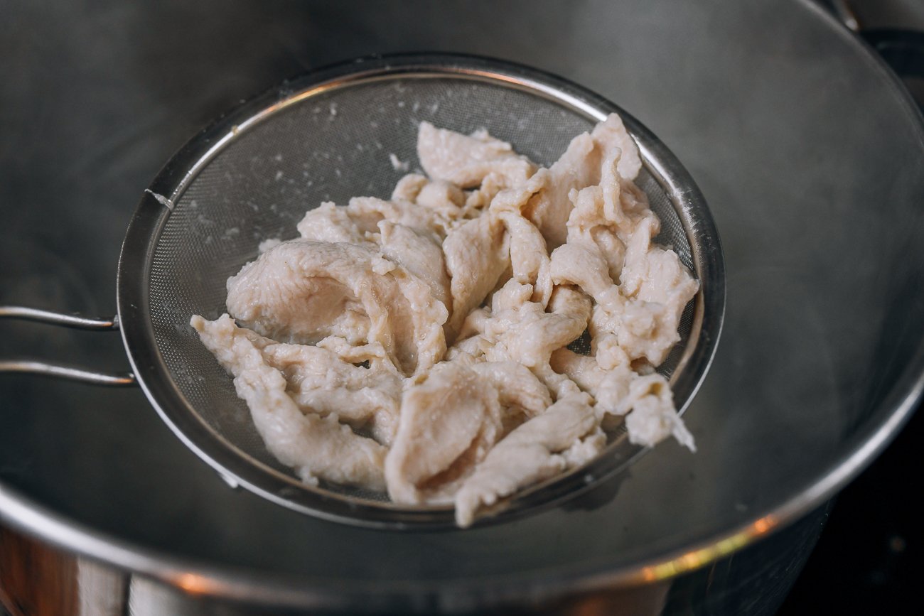 removing cooked chicken from boiling water with a strainer