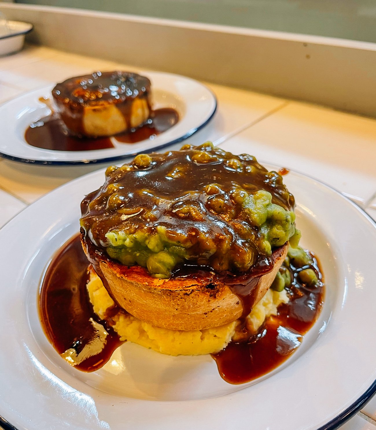 Chicken and Mushroom Pie on top of mashed potatoes, covered in mushy peas and dark brown gravy