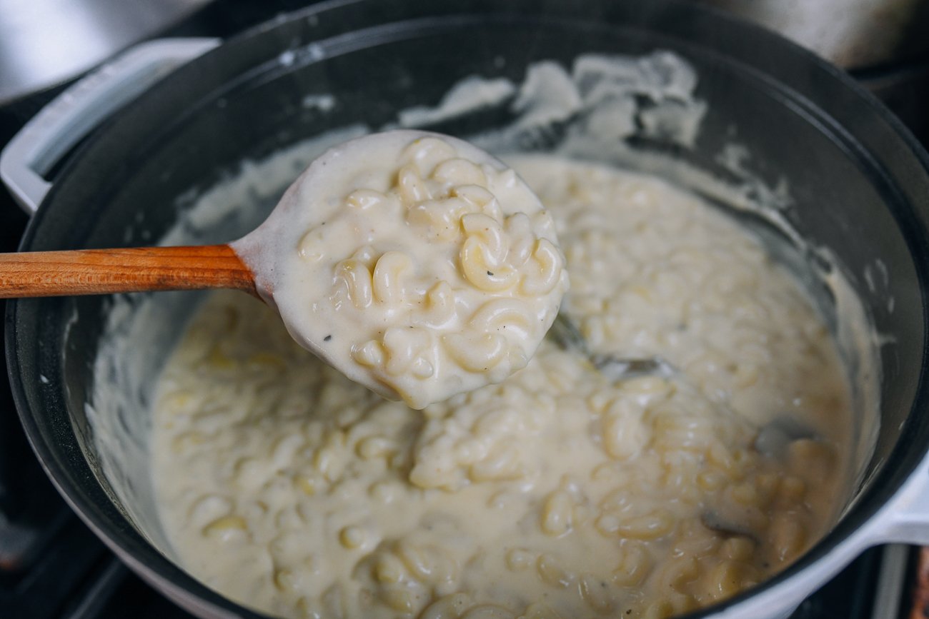 picking up elbow macaroni stirred into white cheese sauce