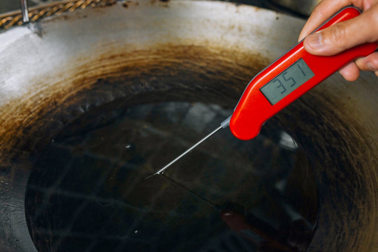 reading oil temperature in wok with instant read thermometer at 350°F