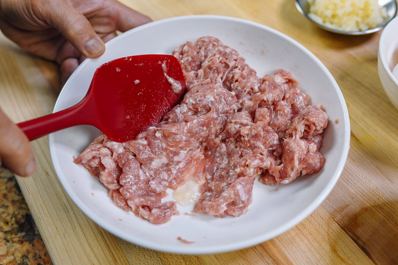 mixing ground pork with rubber spatula