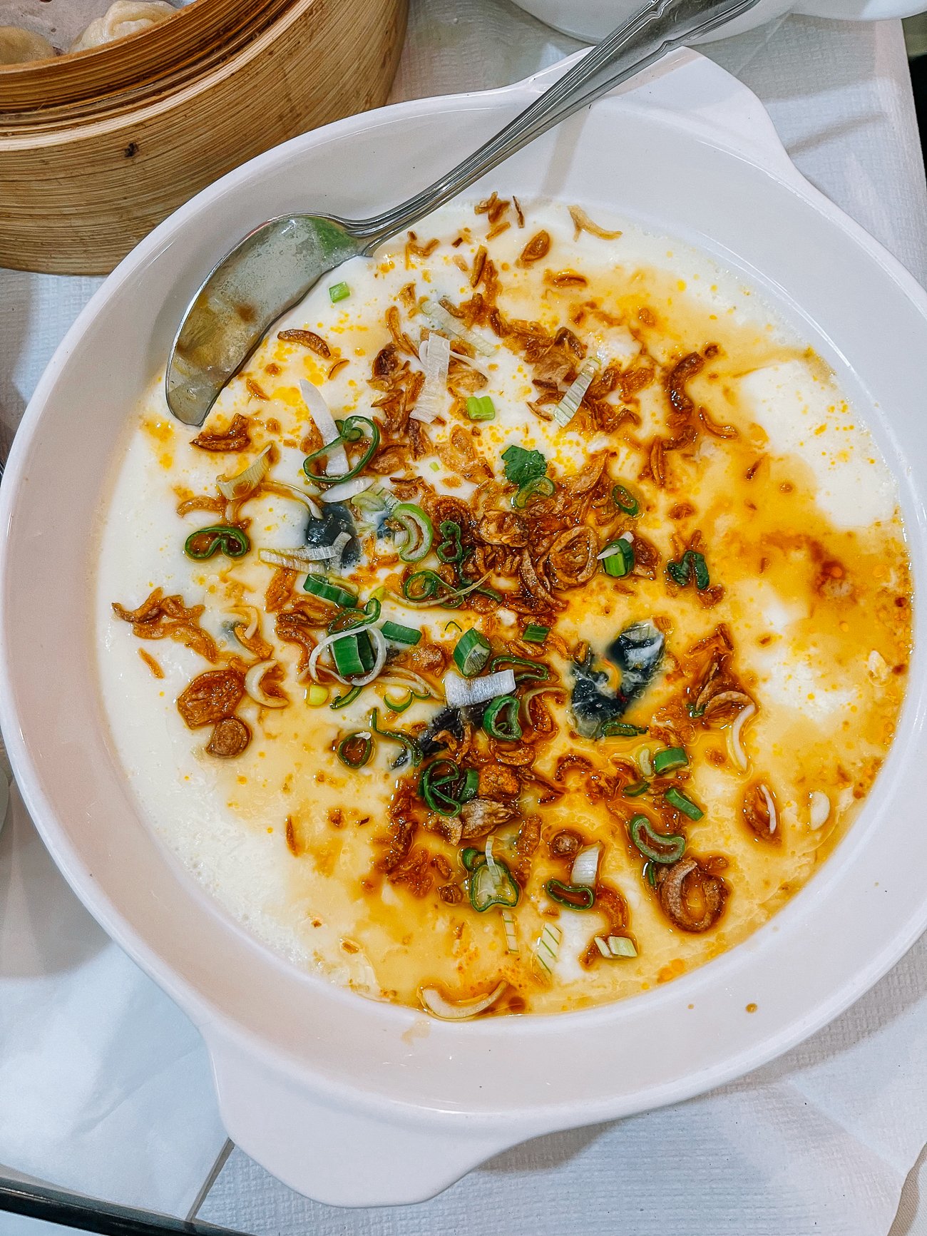 Steamed egg with fried shallots, scallions, and light sauce poured over