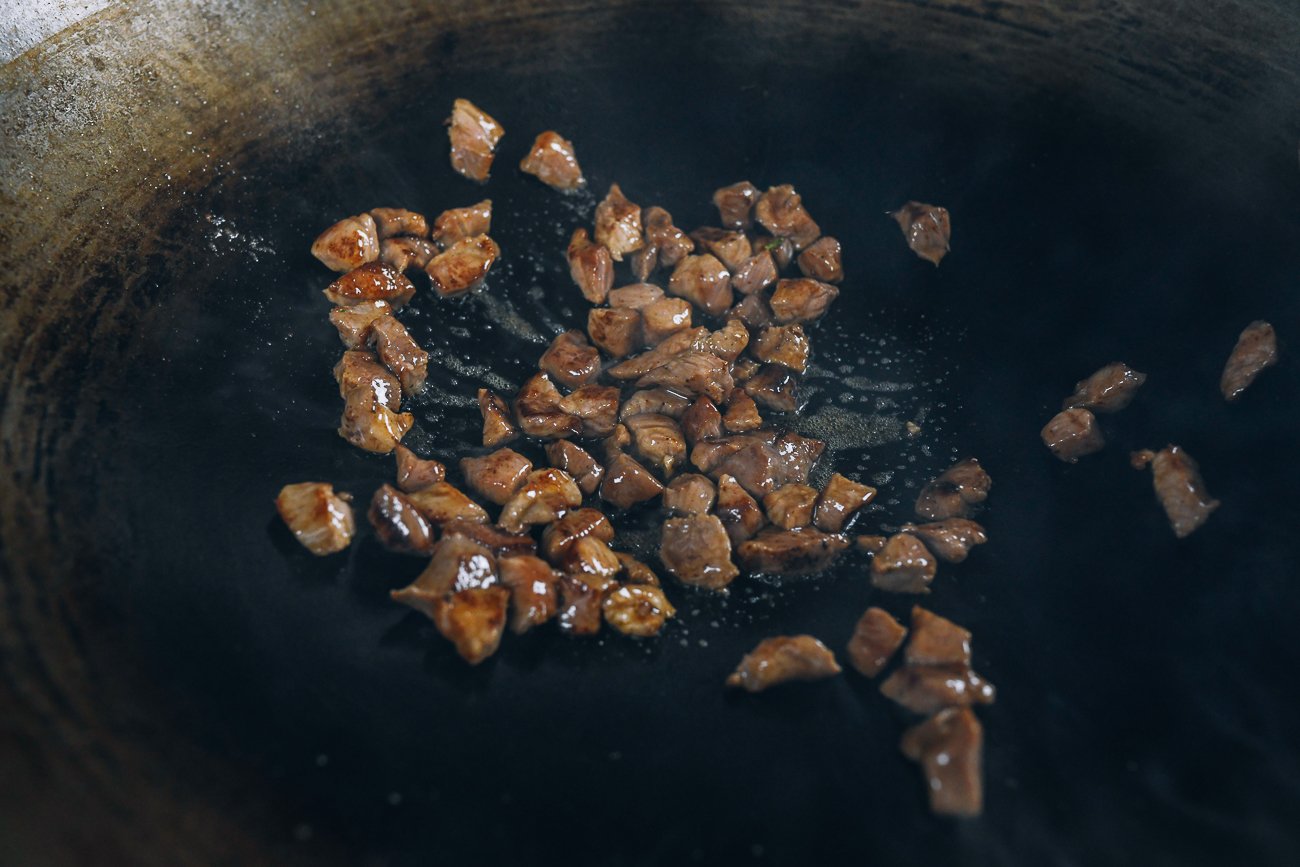 searing pieces of marinated pork in a wok