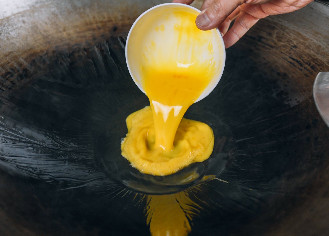 pouring beaten egg into hot wok
