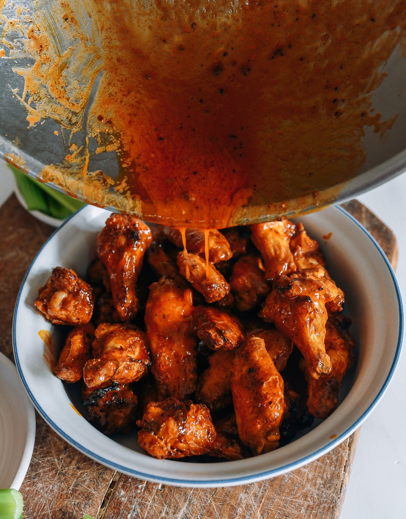 pouring remaining sauce over wings