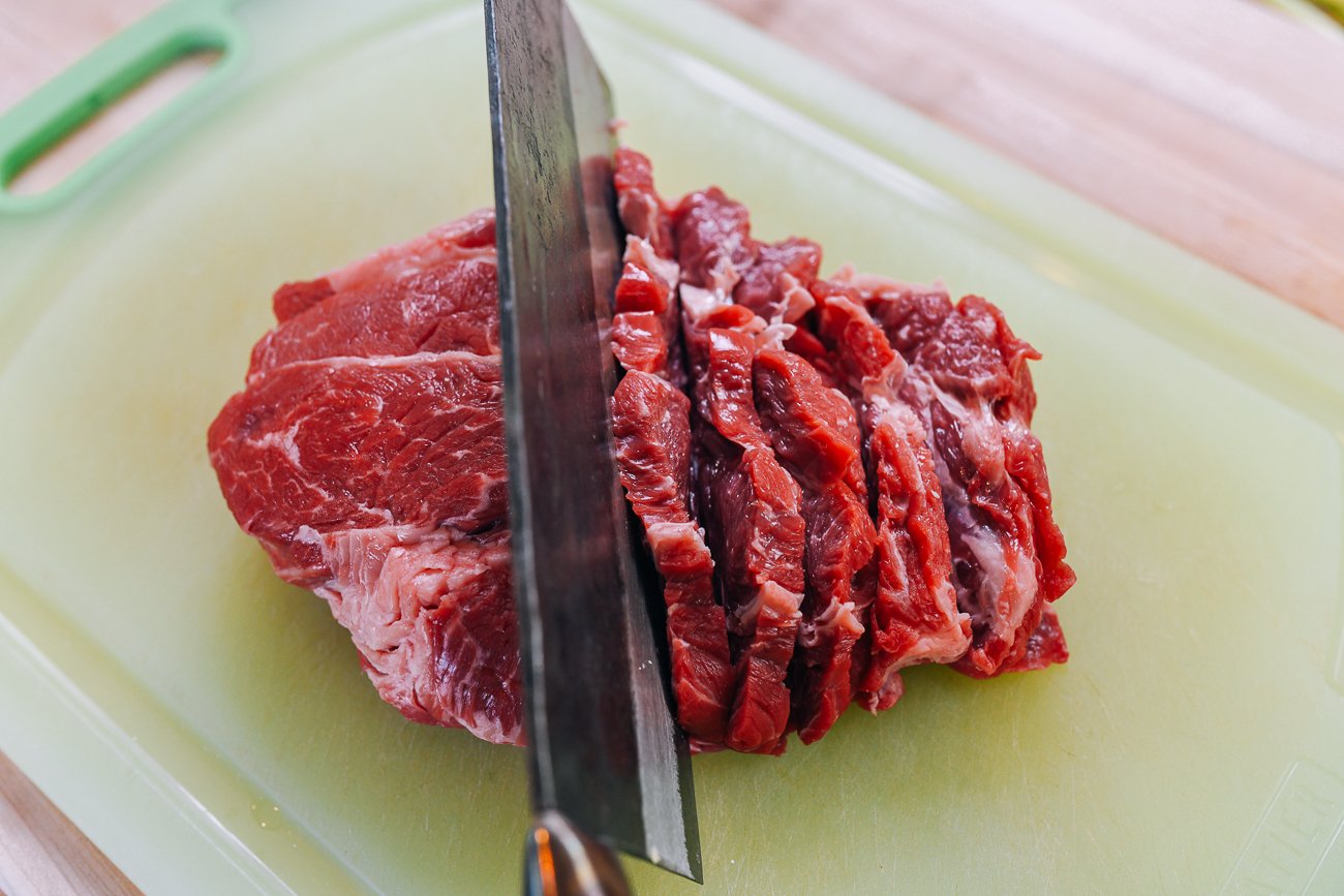 slicing beef chuck on a diagonal with Chinese cleaver