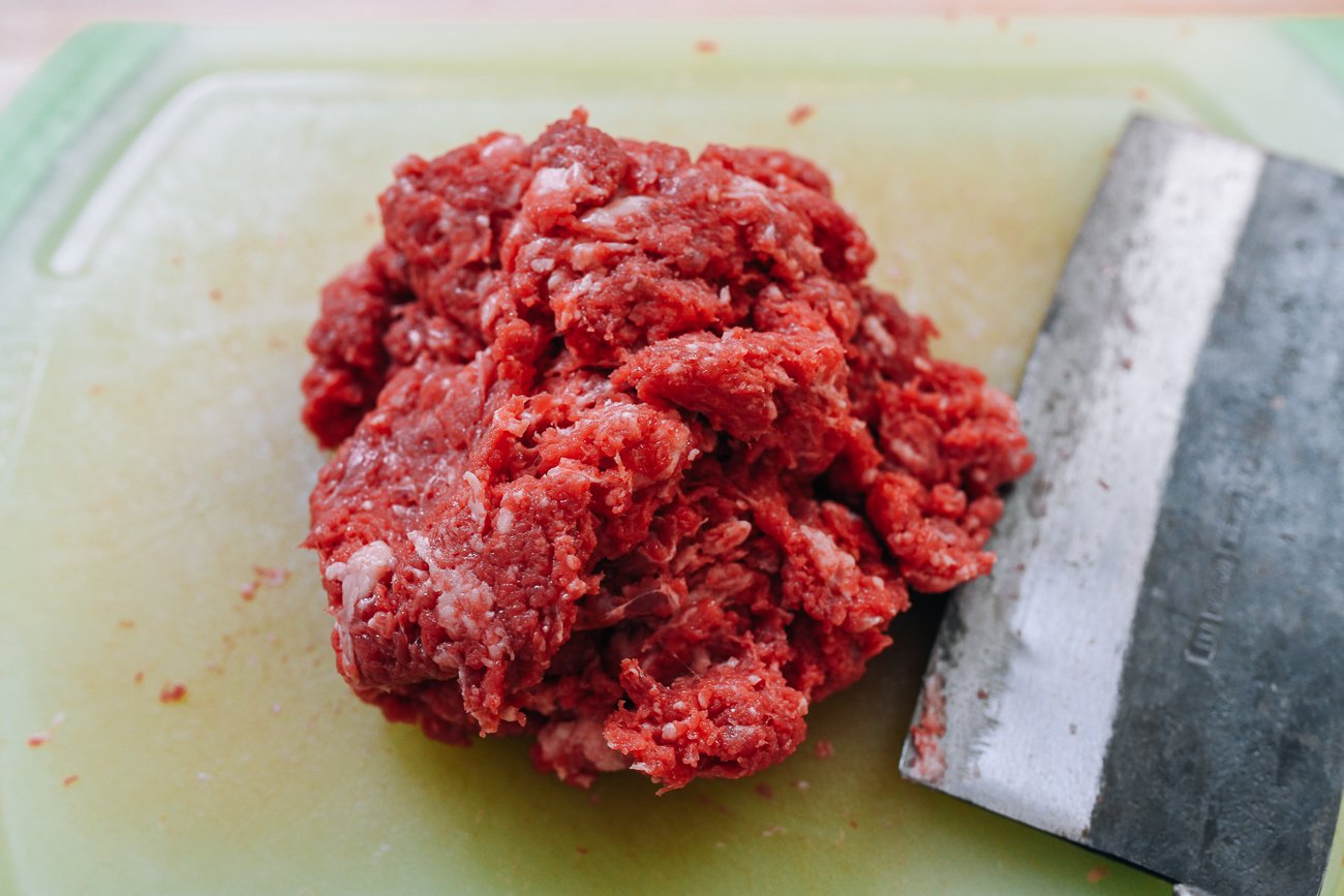 hand-chopped ground beef on cutting board next to Chinese cleaver