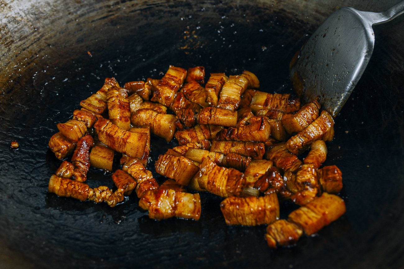 amber colored pork belly pieces in wok