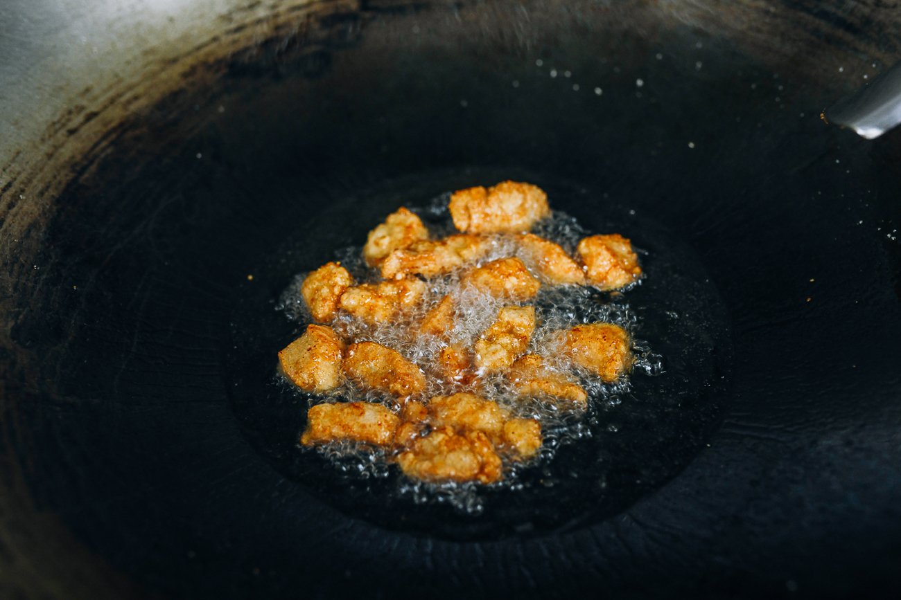 shallow frying chicken pieces in a large wok