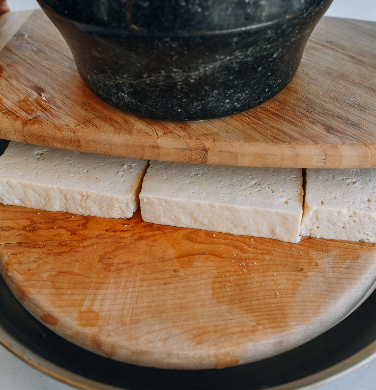 firm tofu pressed between cutting boards with weight on top