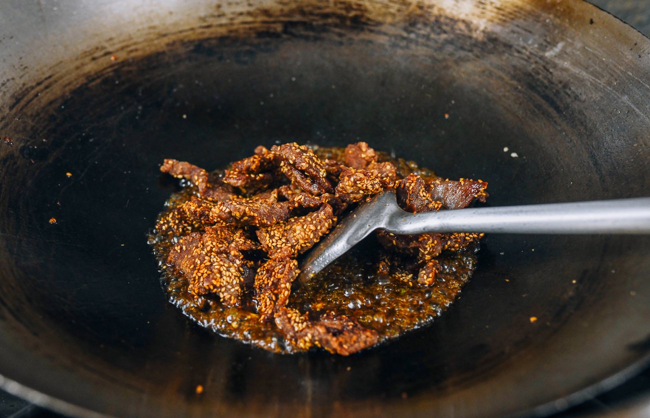 adding sesame crusted beef to wok