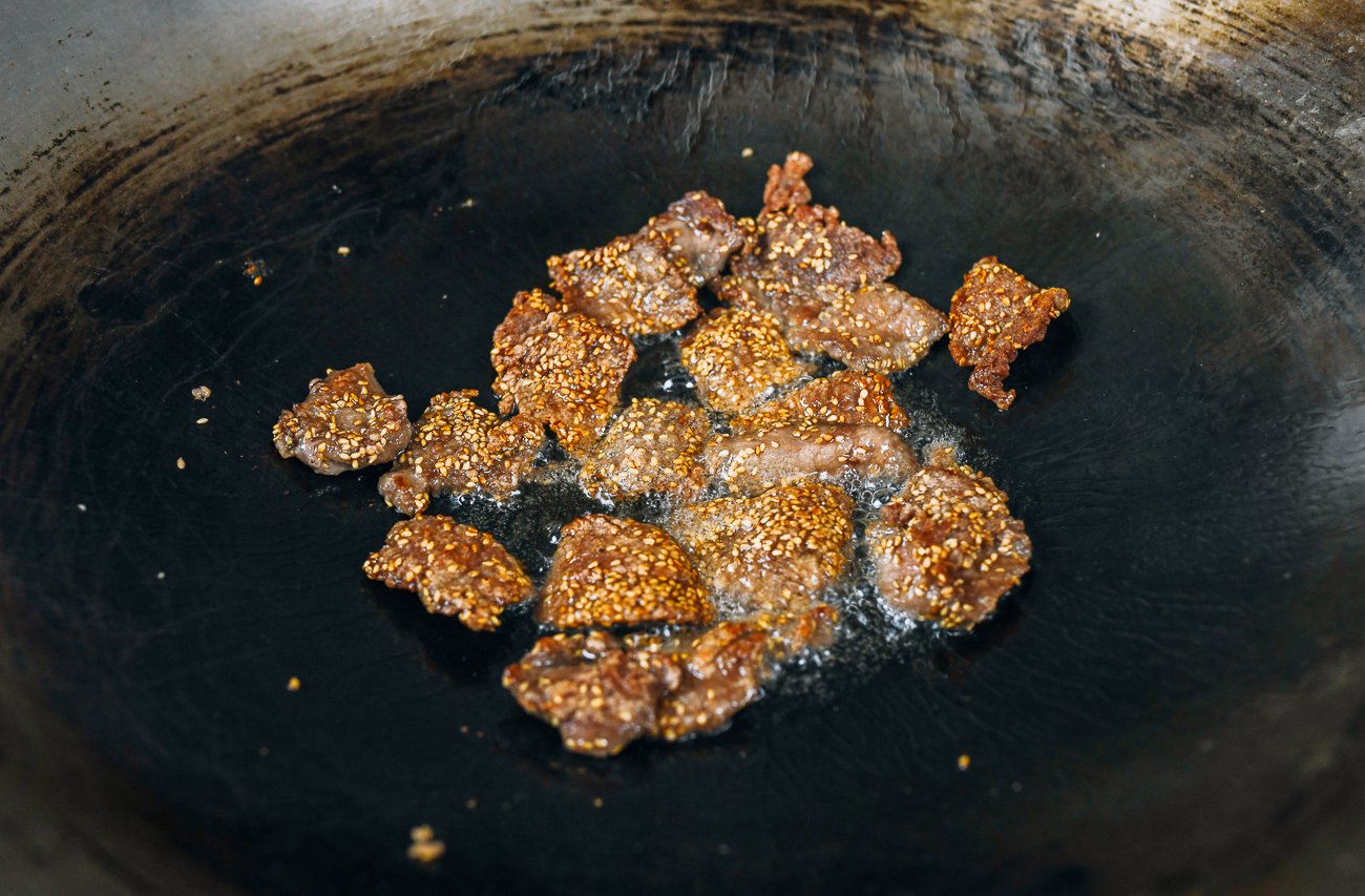 shallow frying sesame crusted beef slices in wok