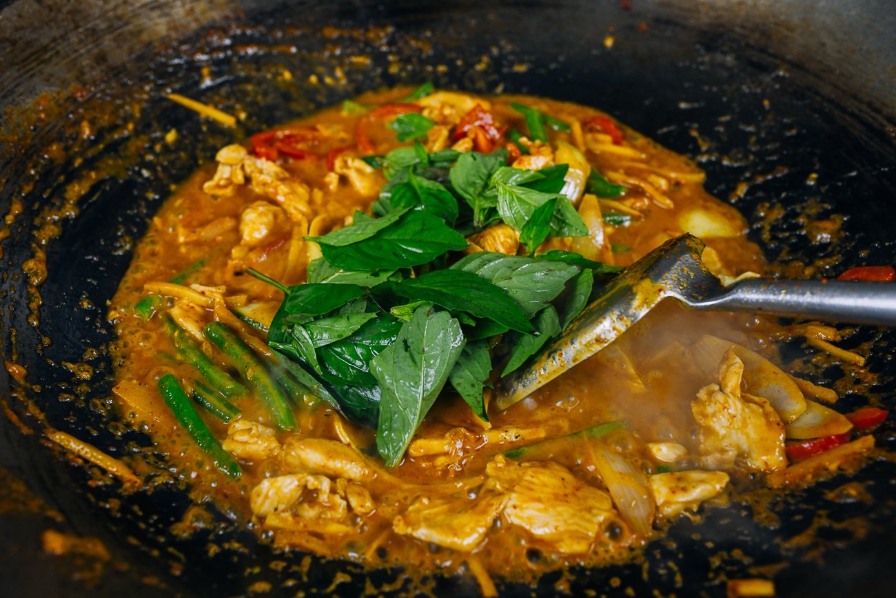 Adding Thai basil leaves to red curry