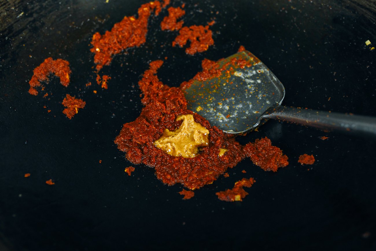 adding palm sugar to red curry paste