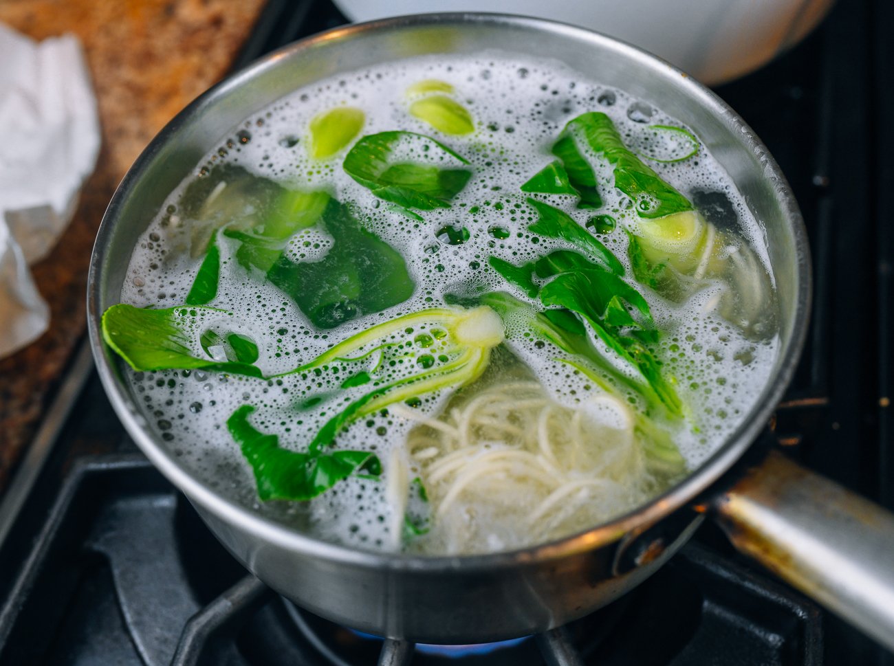 boiling baby bok choy with noodles in pot