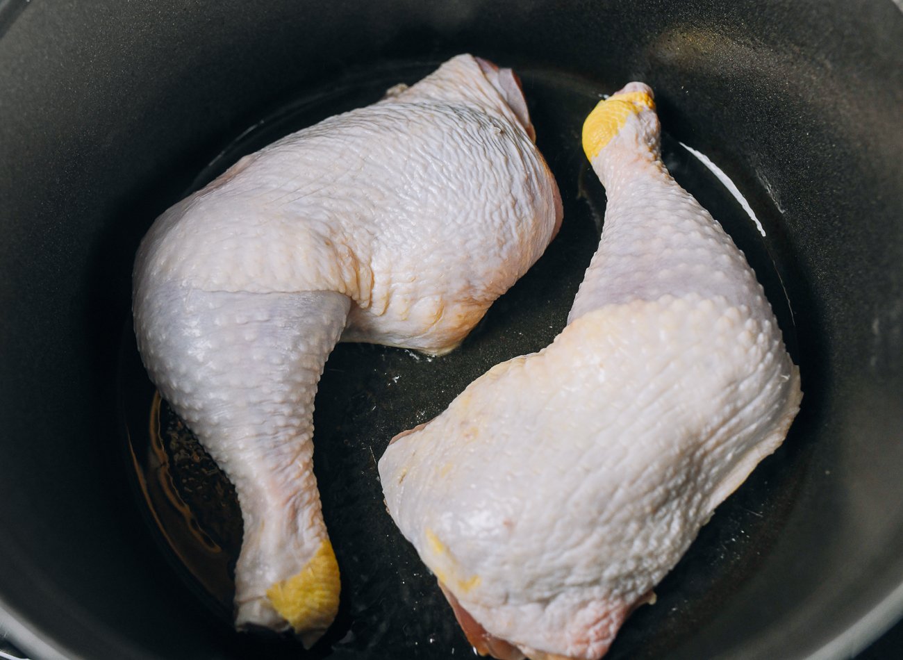 chicken leg quarters cooking in Dutch oven