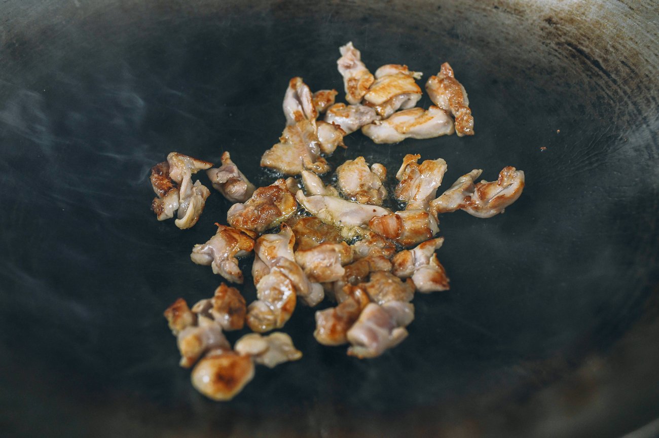 searing chicken pieces in wok