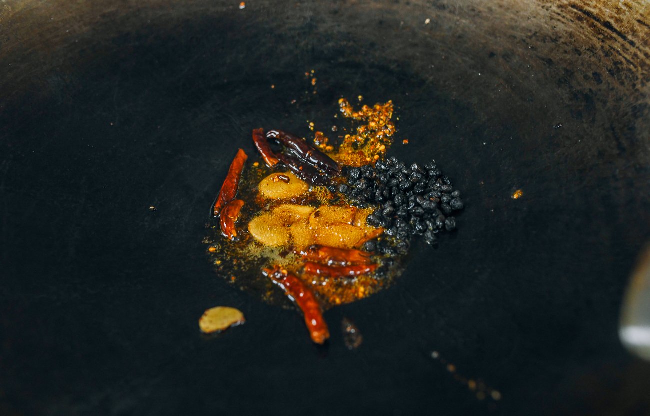 fermented black beans, chili oil, chilies, and ginger in wok