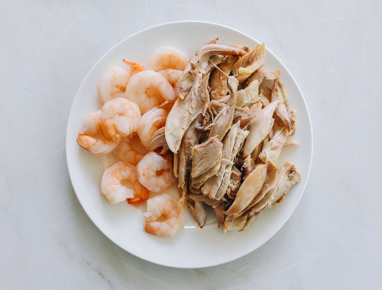 plate with cooked shrimp and sliced Chinese BBQ pork