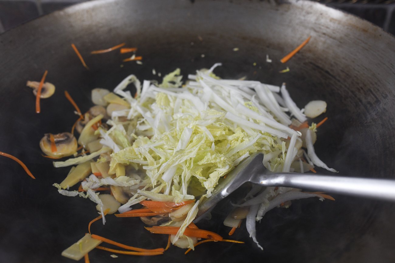 shredded napa cabbage added to wok with other vegetables