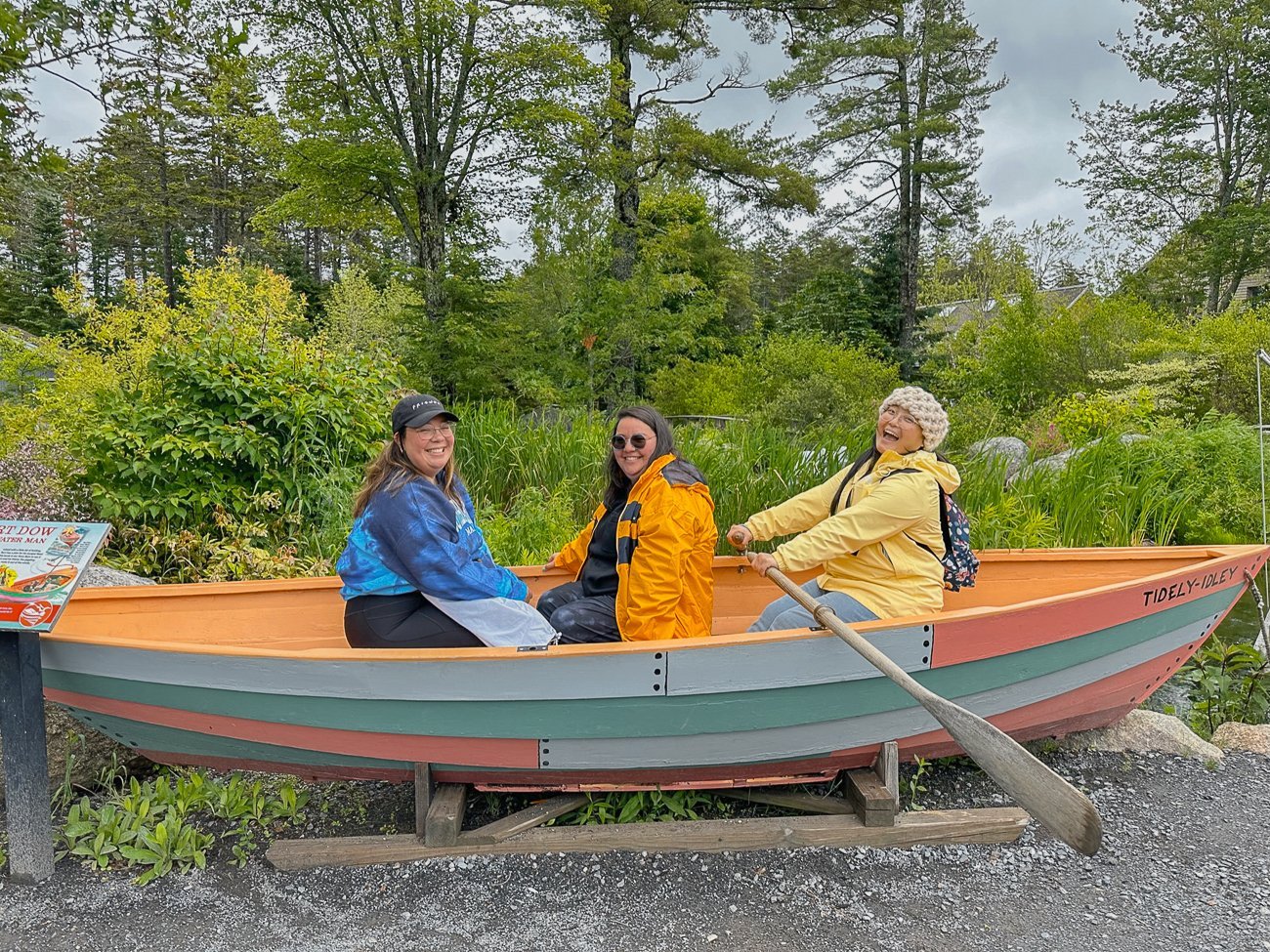 Three women playing in a rowboat at the Coastal Maine Botanical Garden