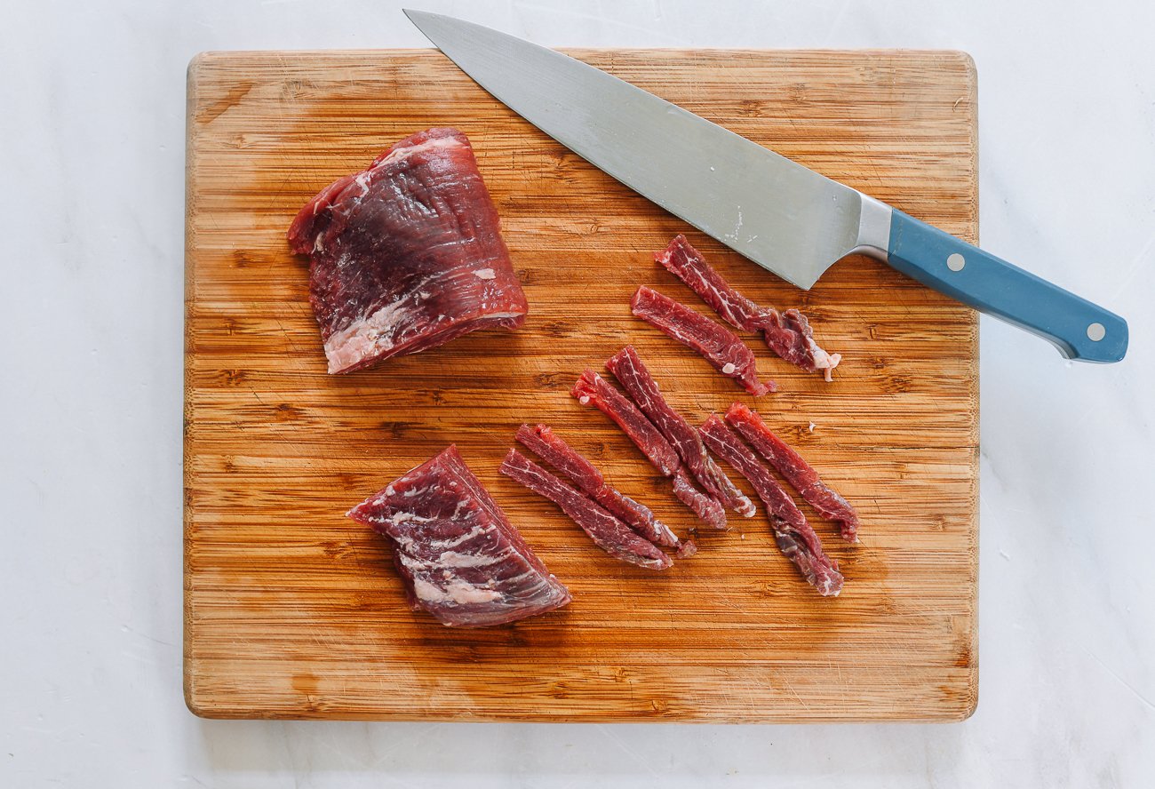 cutting beef flank steak into strips