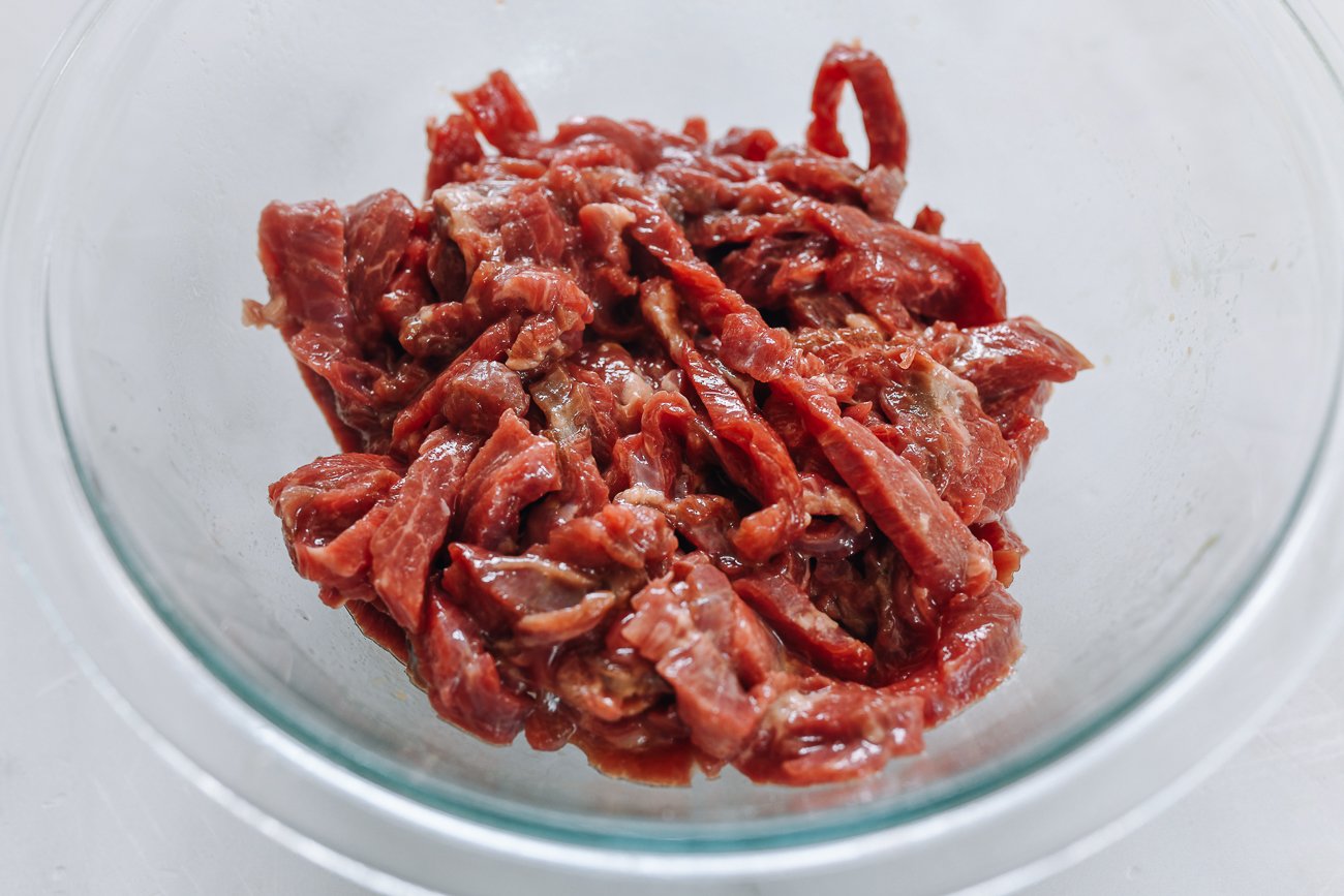 marinating beef strips in glass bowl