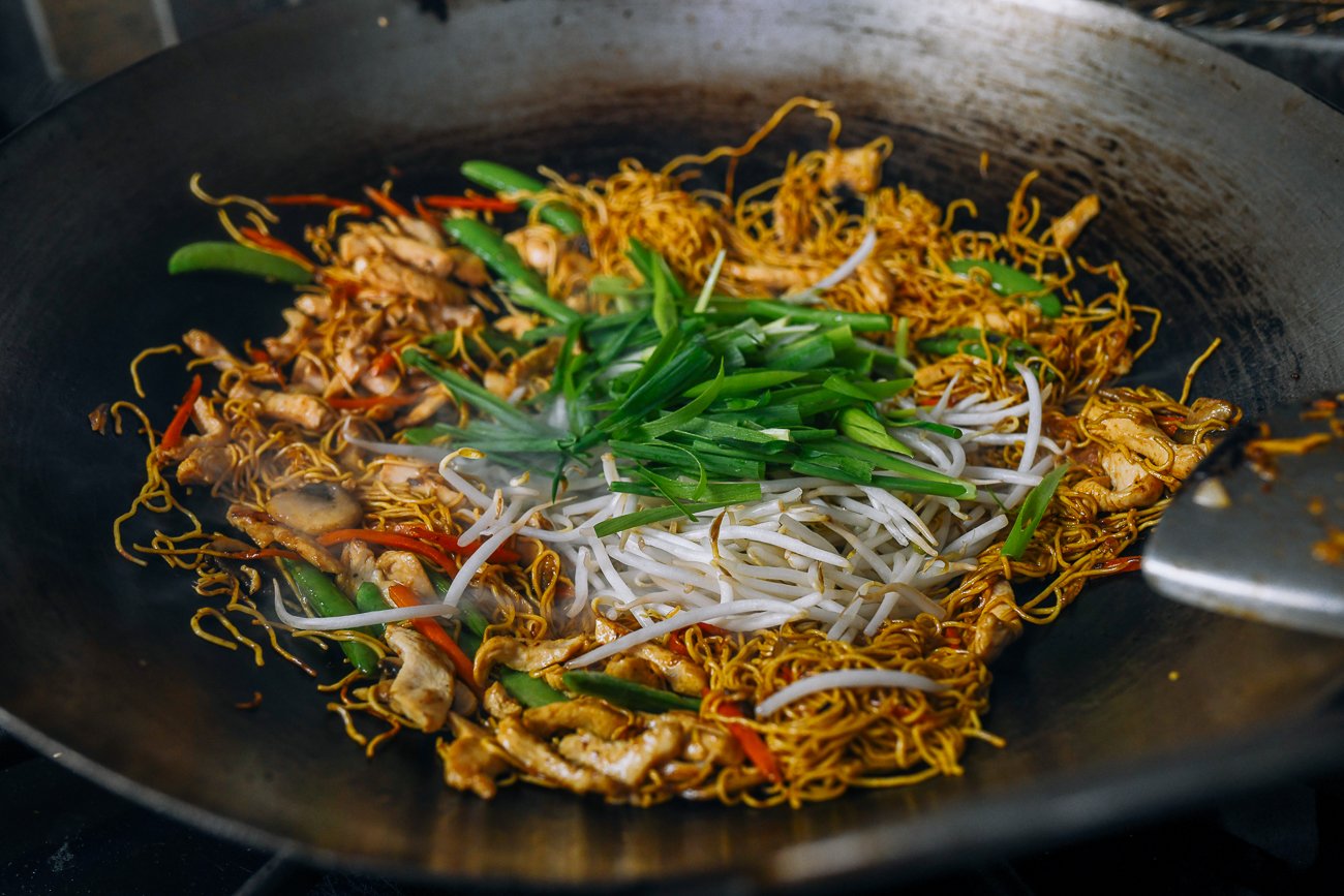 adding scallion and bean sprouts to chicken chow mein