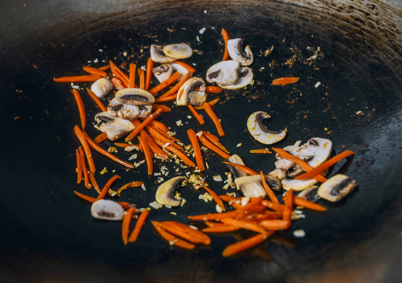 carrots, mushrooms, ginger, and garlic in wok