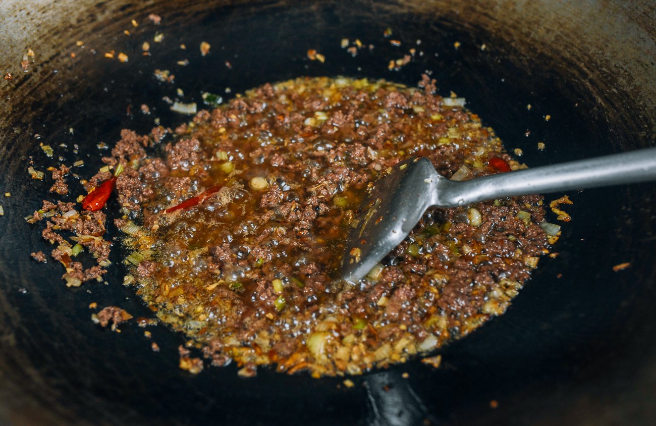 cooking ground meat in oil and aromatics to make Chinese meat sauce