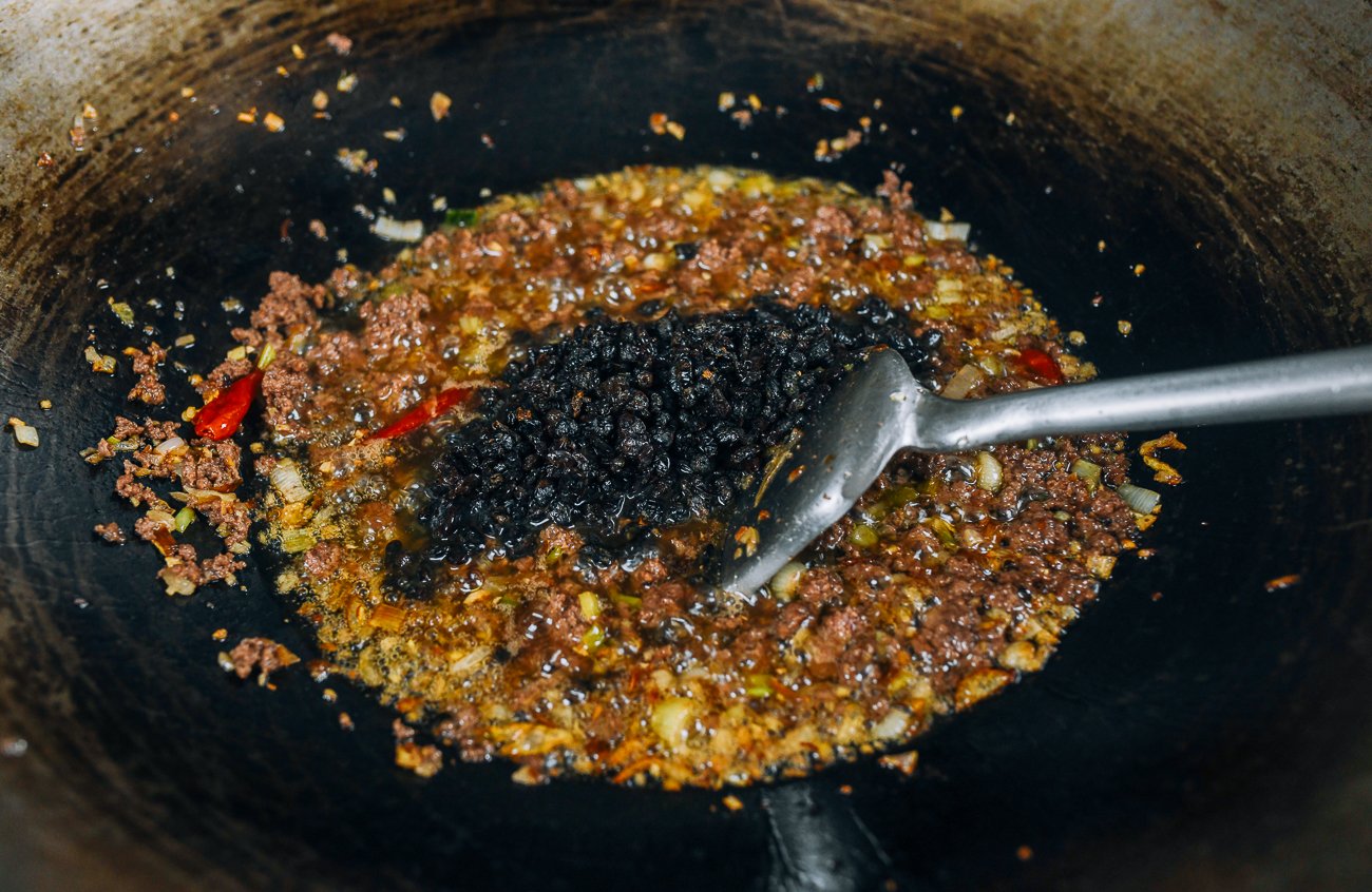fermented black beans added to ground meat, oil, and aromatics