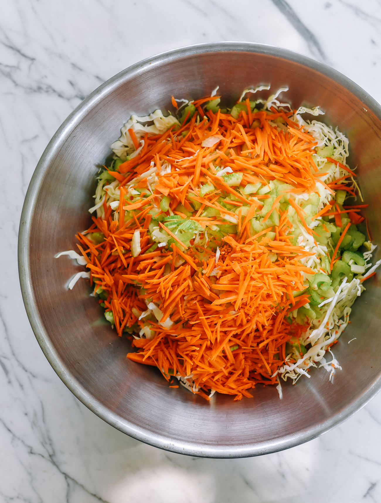 shredded cabbage, carrots, and celery in large metal bowl