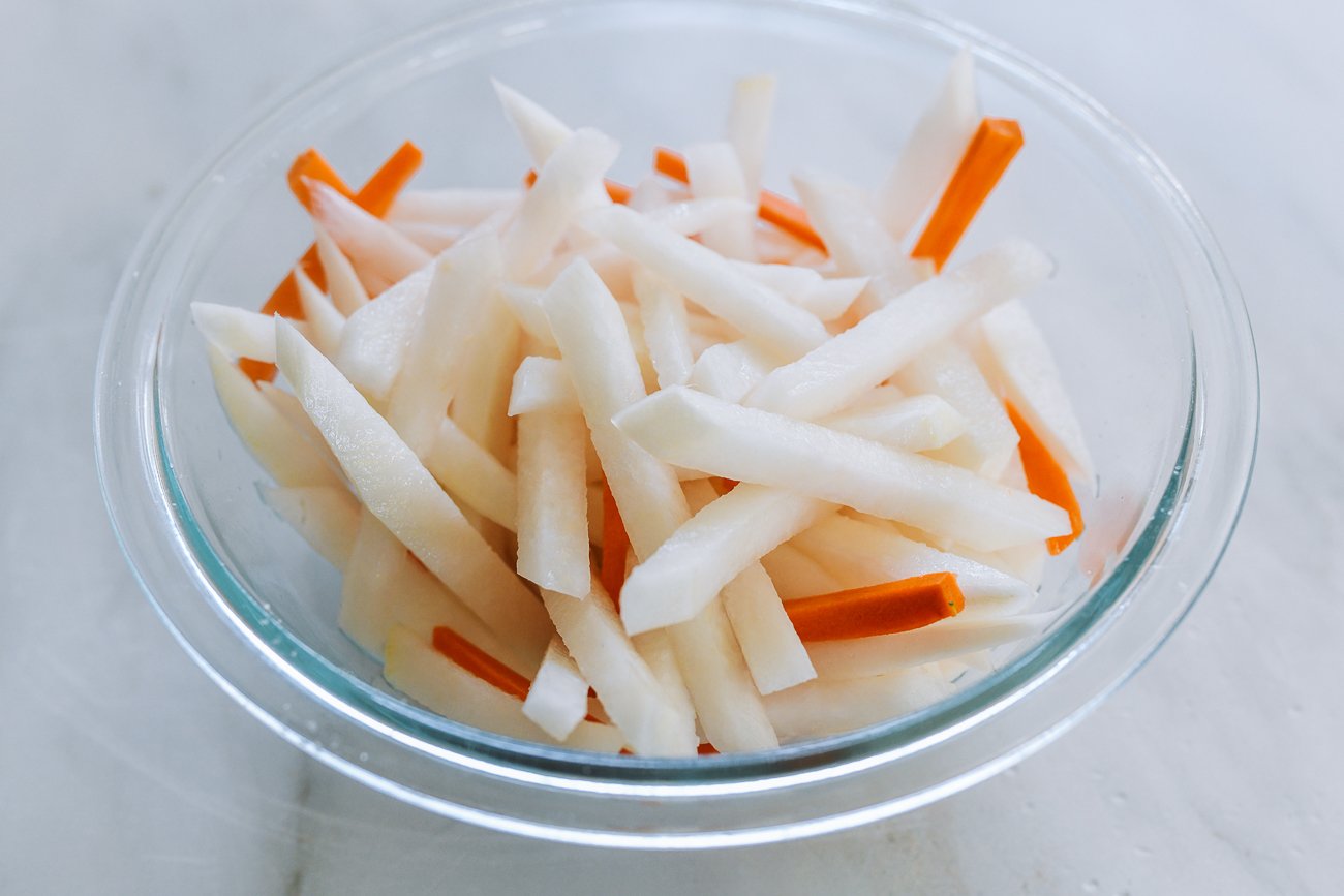 Daikon radish and carrot sticks in glass bowl with salt