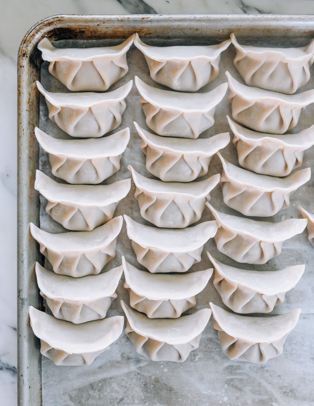 assembled dumplings on parchment lined baking sheet