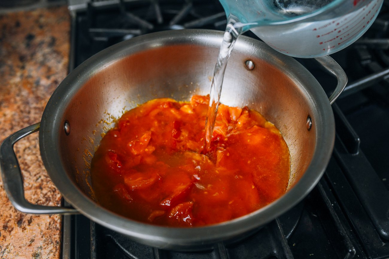 Adding water to tomatoes in pot