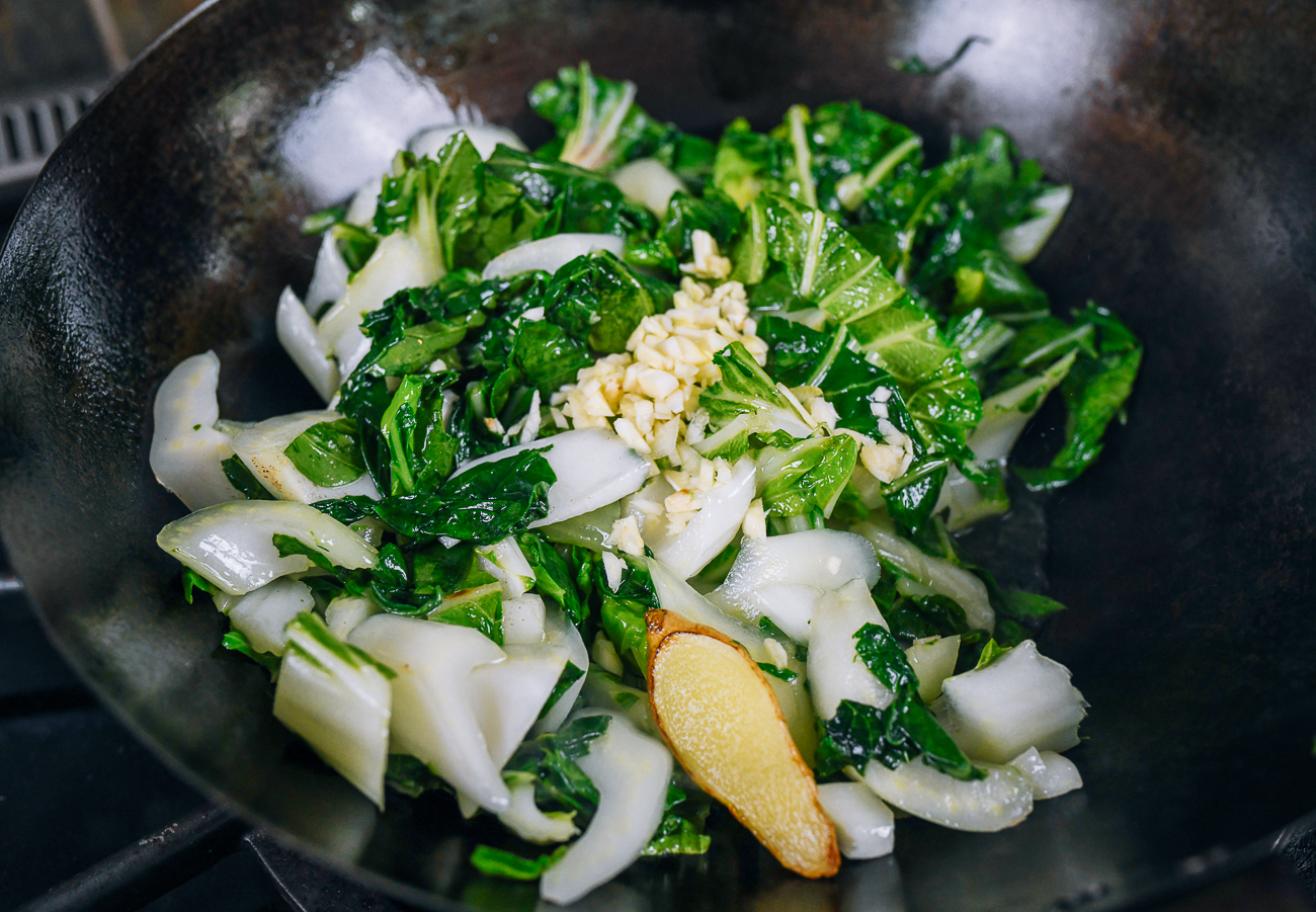 adding garlic to bok choy stir-fry