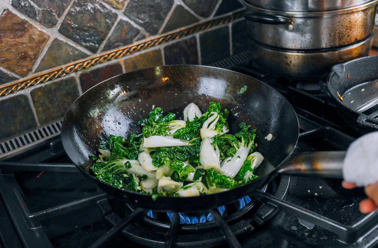 stir-frying bok choy in a wok