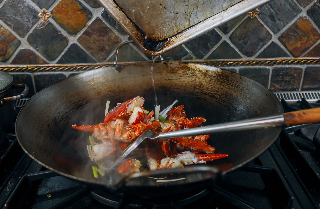 adding lobster to wok with scallions and ginger