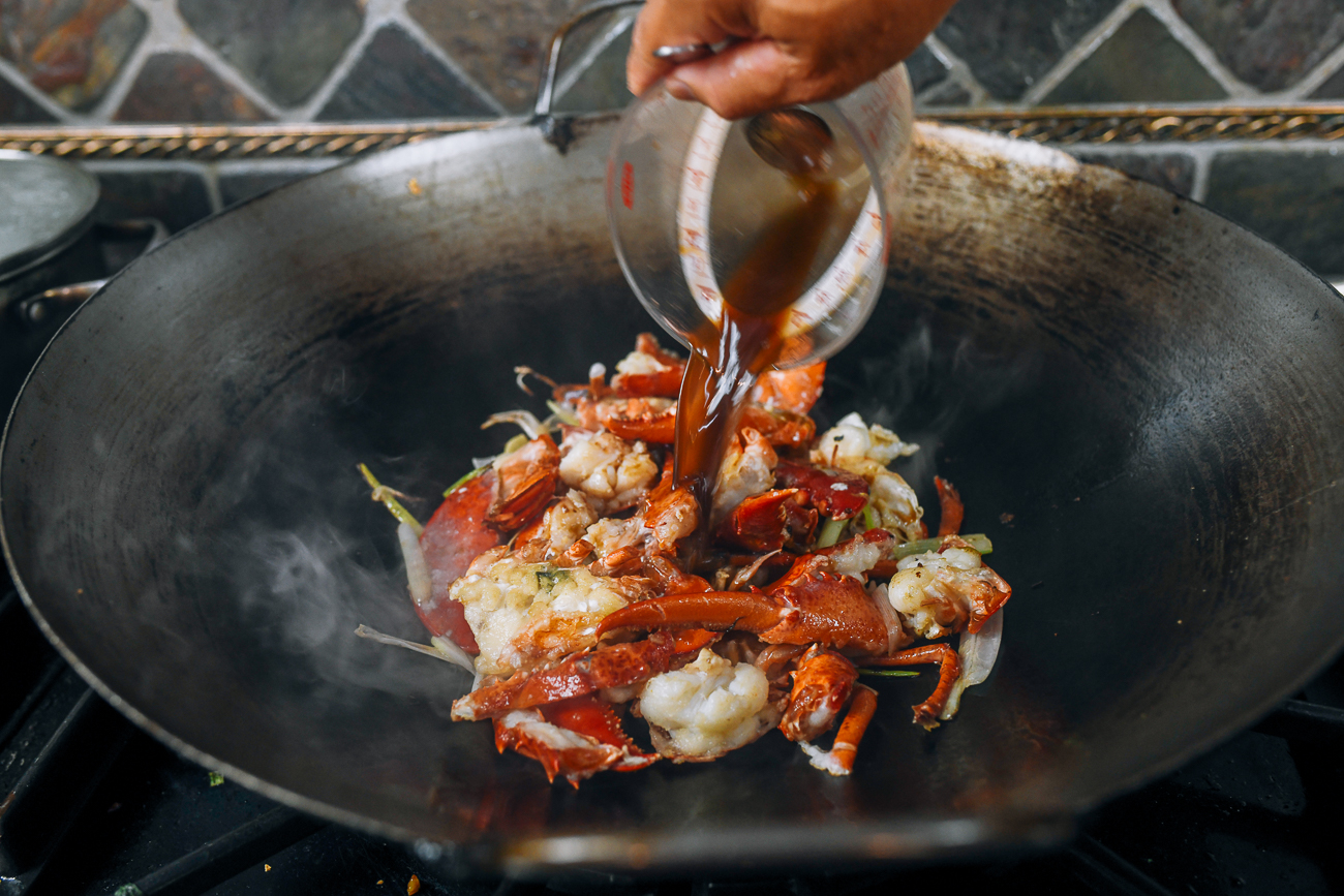 adding sauce mixture to lobster pieces in wok