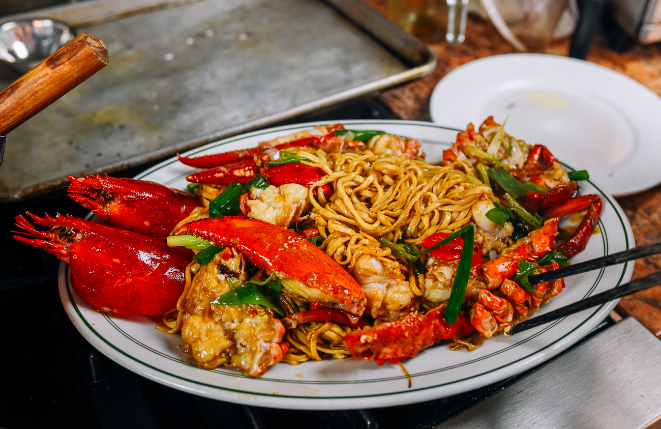 adding lobster on top of yee mein noodles
