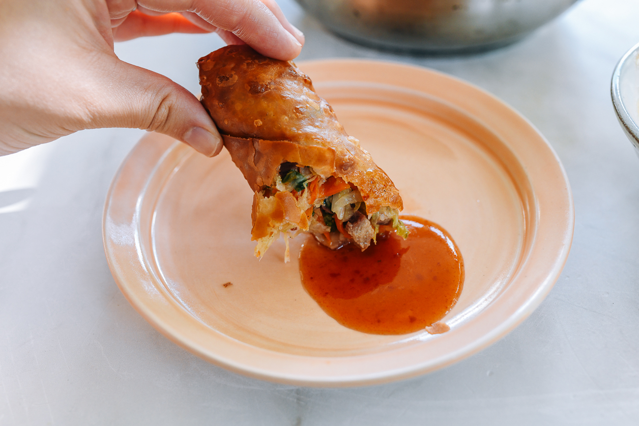 dipping egg roll into sweet and sour sauce