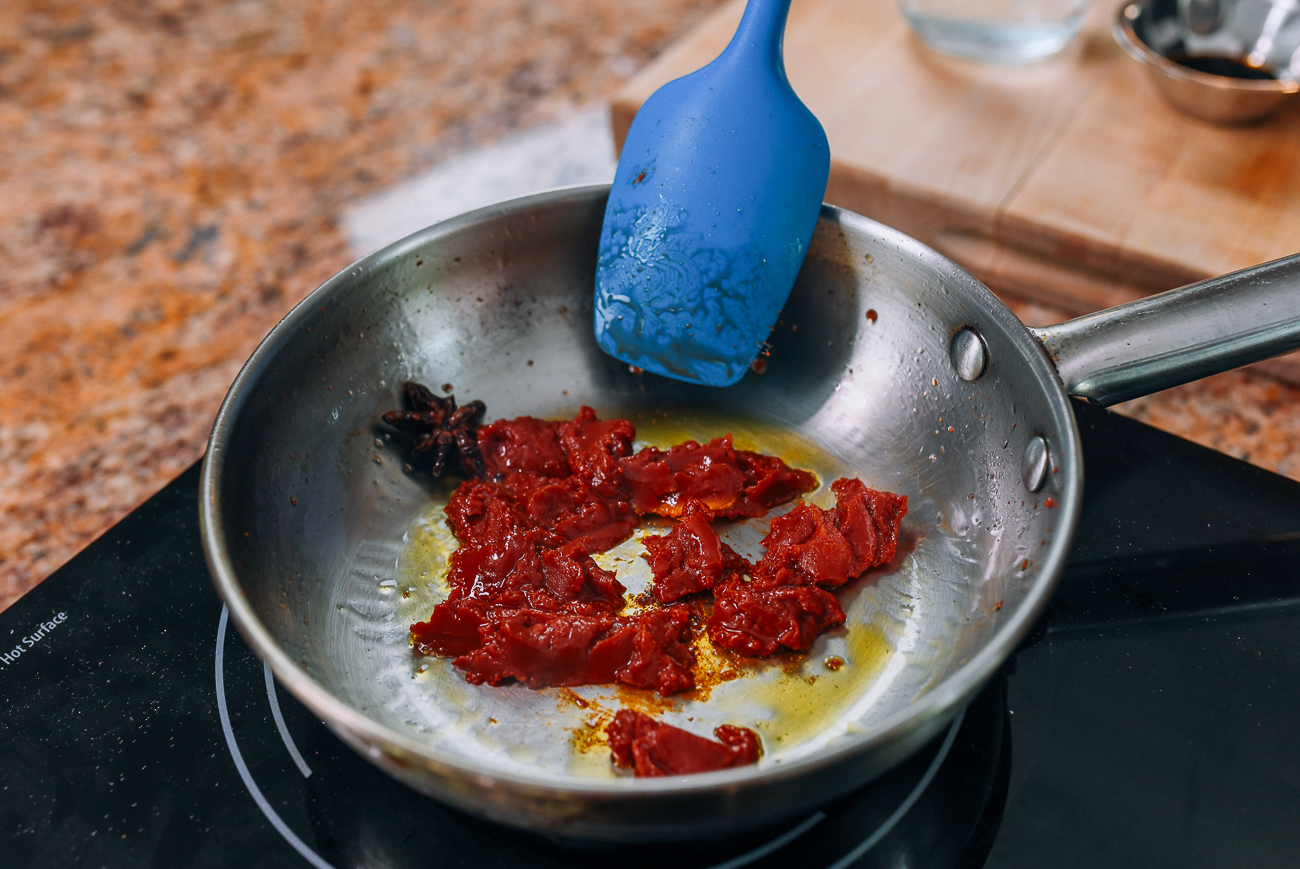 frying tomato paste with star anise and ginger in saucepan