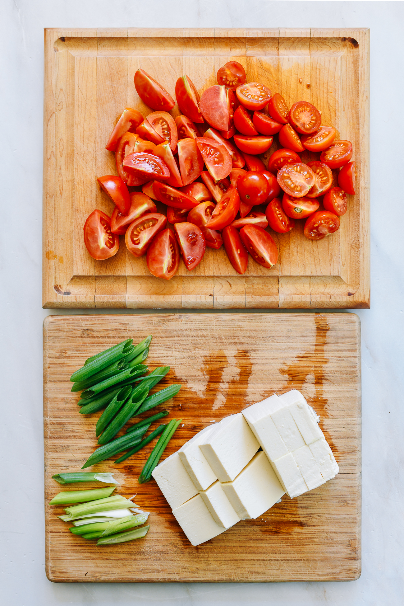 Tomatoes, tofu, and scallions on cutting boards