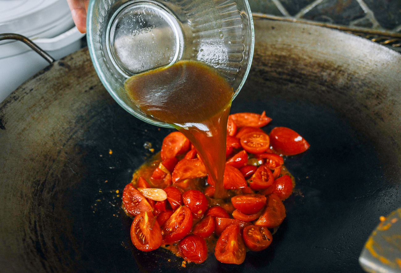adding seasoning ingredients to tomatoes