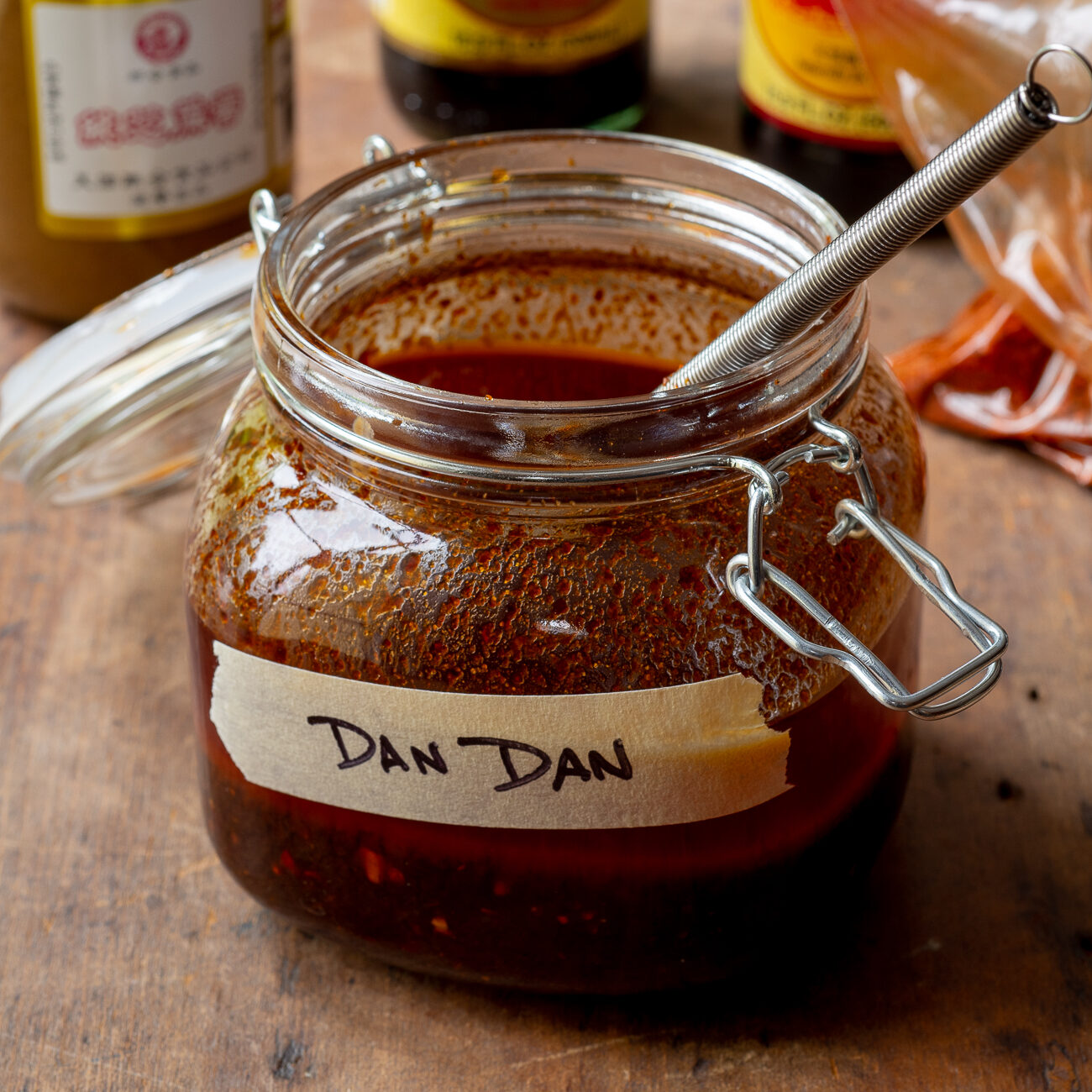 Jar with hinged lid with dark red sauce and masking tape label that says "DAN DAN" 