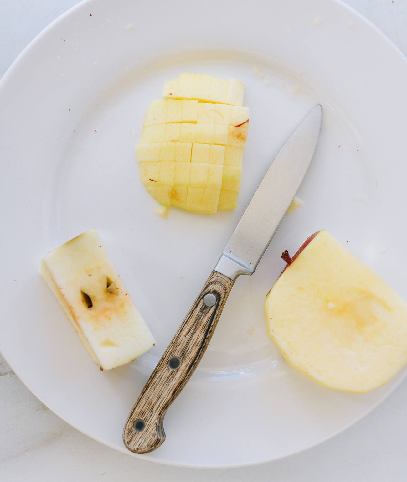 Cut an apple into cubes on a white plate