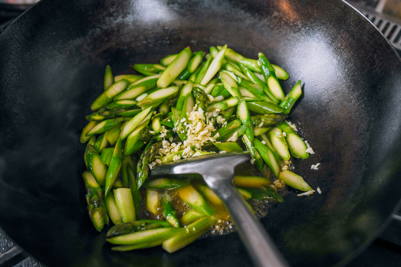 garlic added to asparagus in wok