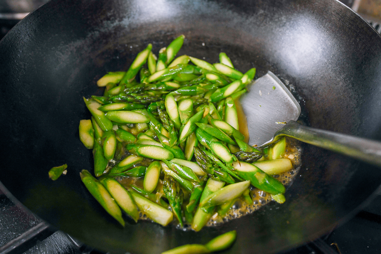 asparagus in wok with garlic and sauce mixture